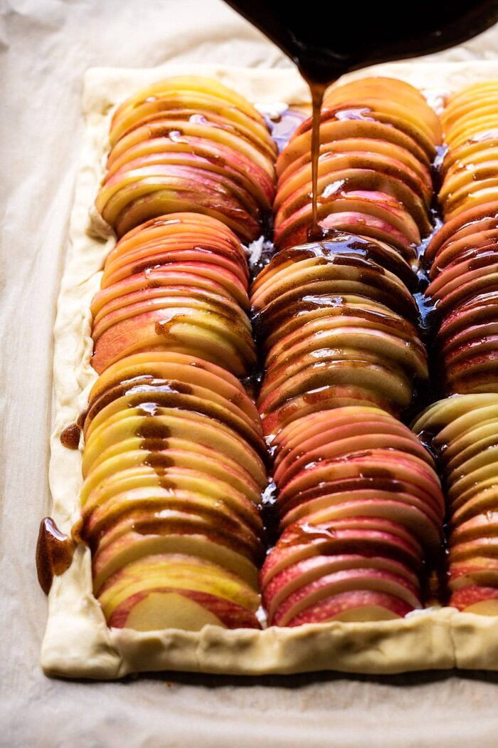 side angled photo of maple syrup being drizzled over top the apples before baking 