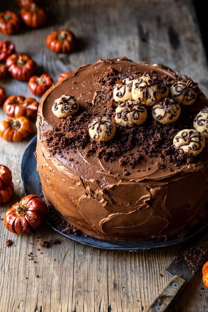 Pumpkin Patch Chocolate Peanut Butter Cake | halfbakedharvest.com #chocolatepeanutbutter #chocolatecake #peanutbutter #halloween 3/4 angle photo of Pumpkin Patch Chocolate Peanut Butter Cake with mini pumpkins on table