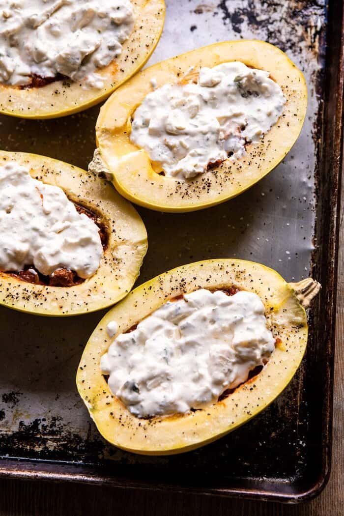 Roasted Garlic Spaghetti Squash Lasagna Boats | halfbakedharvest.com #healthyrecipes #spaghettisquash #fall #easyrecipes overhead photo of Roasted Garlic Spaghetti Squash Lasagna Boats before baking with cheese sauce