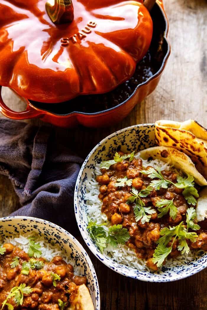 side angled photo of 30 Minute Indian Pumpkin Butter Chickpeas with 2 bowls and pumpkin pot on surface