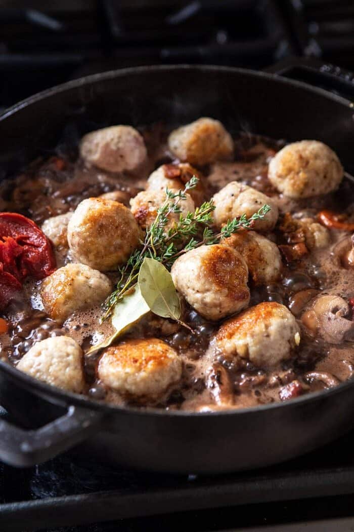 30 Minute Coq au Vin Chicken Meatballs with browned Butter Mashed Potatoes | halfbakedharvest.com #meatballs #easyrecipe #dinner side angle photo of adding meatballs to skillet