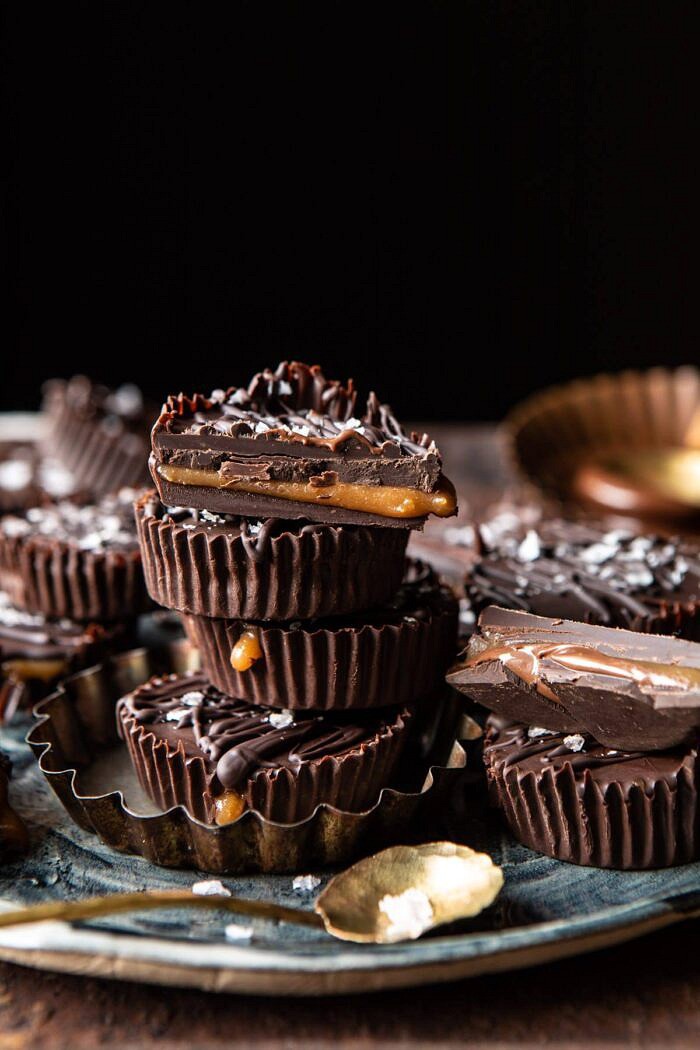6 Ingredient Milk Chocolate Salted Caramel Cups | halfbakedharvest.com #chocolate #caramel #easy #fall side angled photo of 6 Ingredient Milk Chocolate Salted Caramel Cups stack on top of each other with one caramel cup cut in half