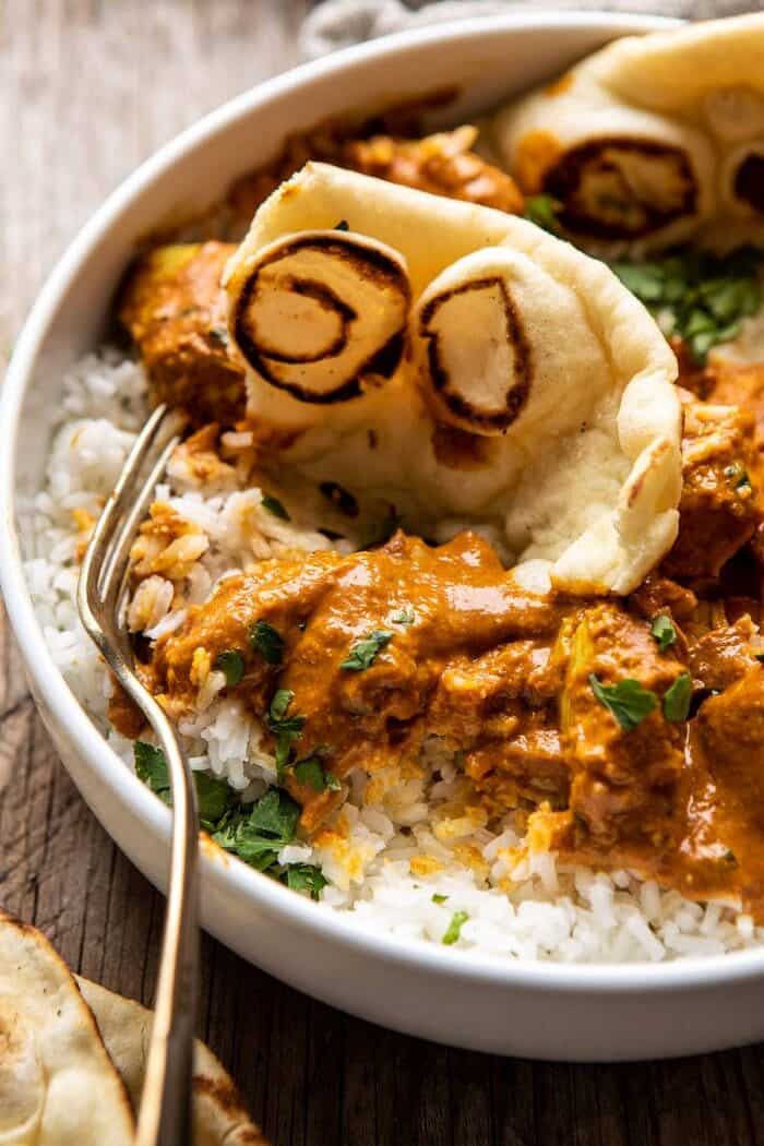 side angled close up photo of Super Simple Coconut Chicken Tikka Masala with fork in bowl 