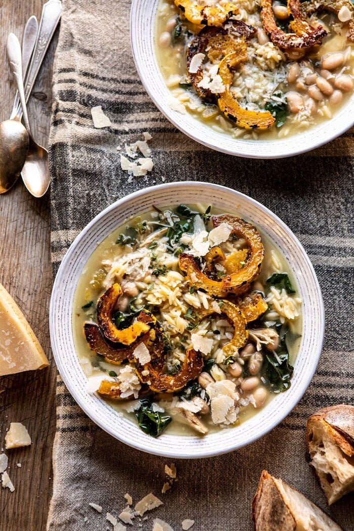 Crockpot Parmesan White Bean Chicken Soup with Roasted Delicata Squash | halfbakedharvest.com #crockpot #slowcooker #instantpot #chickensoup overhead photo of Crockpot Parmesan White Bean Chicken Soup with Roasted Delicata Squash with 2 bowls in photo