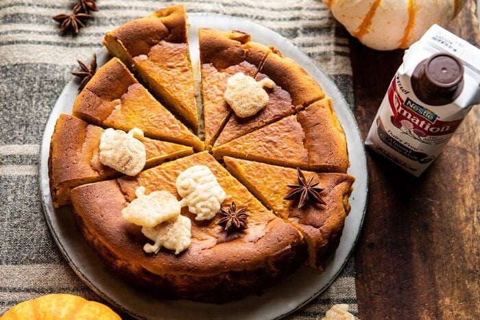 Burnt Basque Pumpkin Spice Cheesecake | halfbakedharvest.com #pumpkin #cheesecake #thanksgiving horizontal photo of Burnt Basque Pumpkin Spice Cheesecake with almond milk in photo next to cheesecake