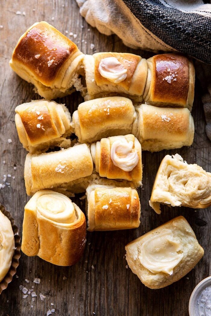 Salted Honey Butter Parker House Rolls | halfbakedharvest.com #rolls #thanksgiving #holidayrecipe overhead photo of Salted Honey Butter Parker House Rolls with a few rolls torn apart