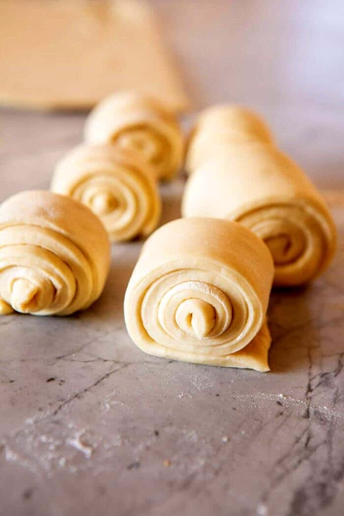 Salted Honey Butter Parker House Rolls | halfbakedharvest.com #rolls #thanksgiving #holidayrecipe side angled, close up photo of Salted Honey Butter Parker House Roll dough before baking, process shot