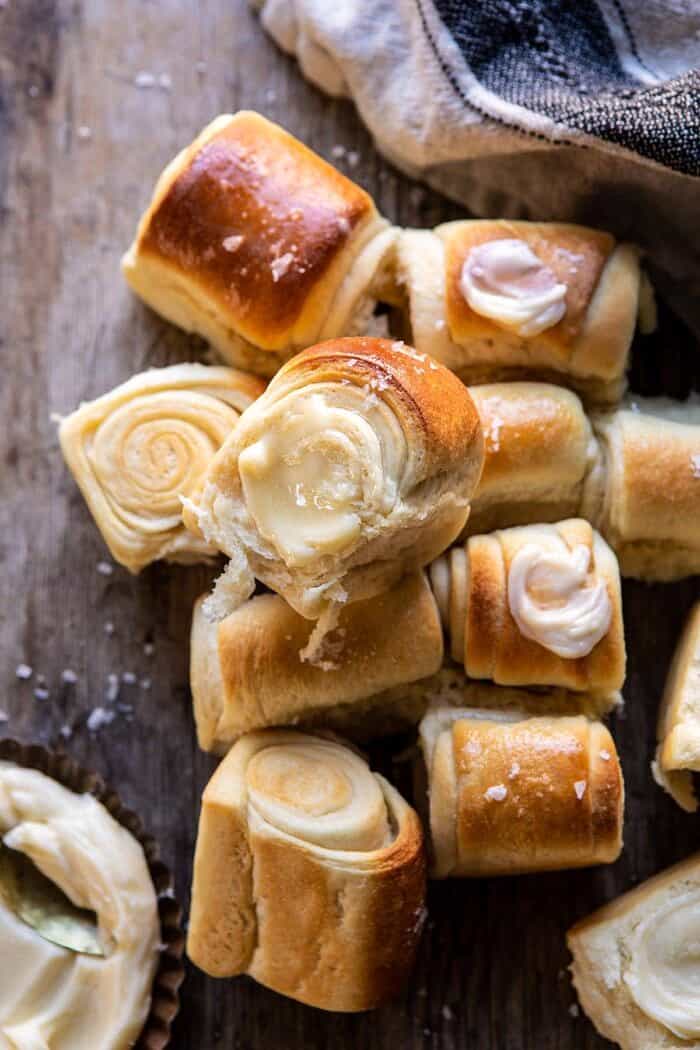 Salted Honey Butter Parker House Rolls | halfbakedharvest.com #rolls #thanksgiving #holidayrecipe overhead close up photo of Salted Honey Butter Parker House Roll with butter on roll