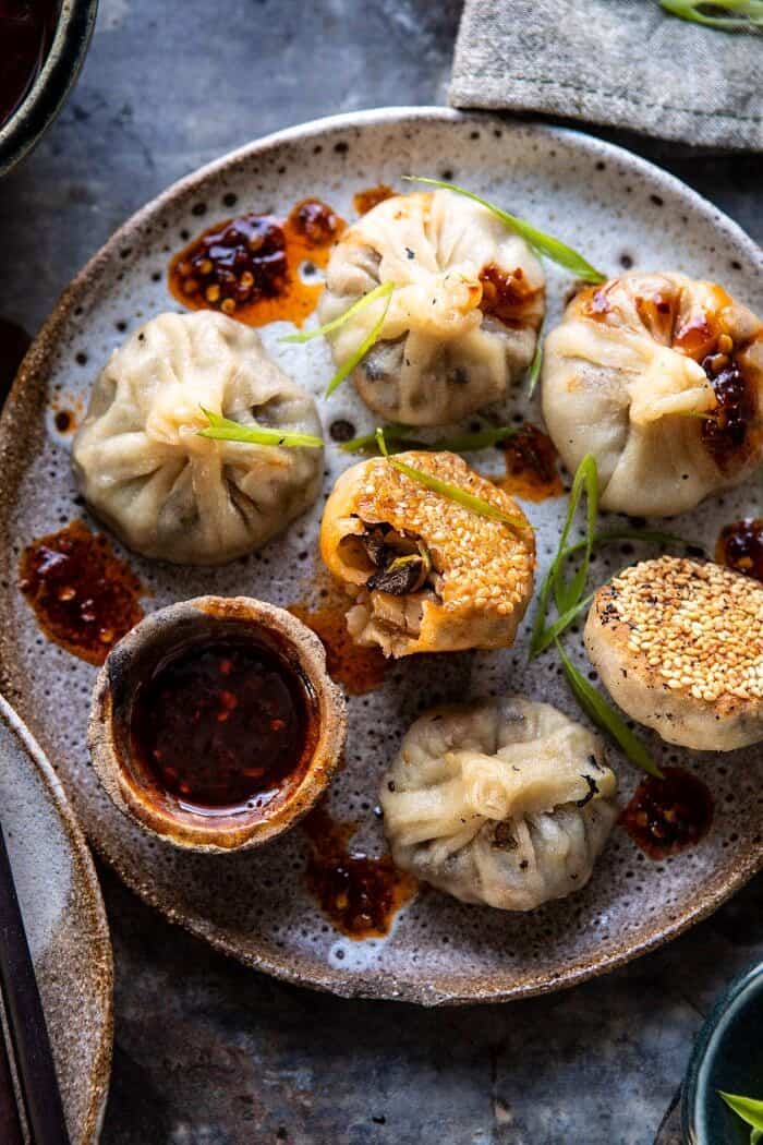 Chinese Mushroom Dumplings with Sweet Chili Ginger Sesame Sauce | halfbakedharvest.com #dumplings #potstickers #chinese overhead photo of Chinese Mushroom Dumplings with Sweet Chili Ginger Sesame Sauce and bite taken out of dumpling