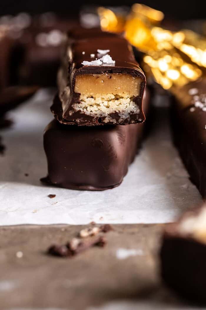Homemade Vegan Twix Bars | halfbakedharvest.com #vegan #chocolatebar side angled photo of Homemade Vegan Twix Bars with 1 bar cut in half to expose the filling