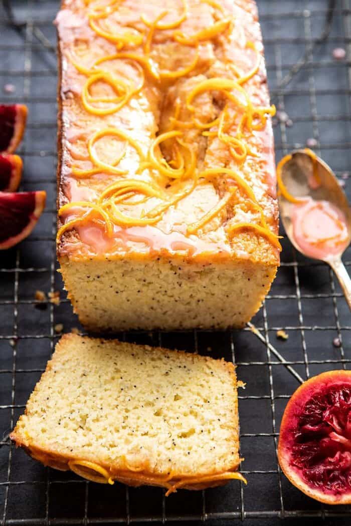 Lemon Poppyseed Cake with Citrus Honey Glaze | halfbakedharvest.com #lemon #cake #winter side angled photo of Lemon Poppyseed Cake with Citrus Honey Glaze with 1 piece of cake cut
