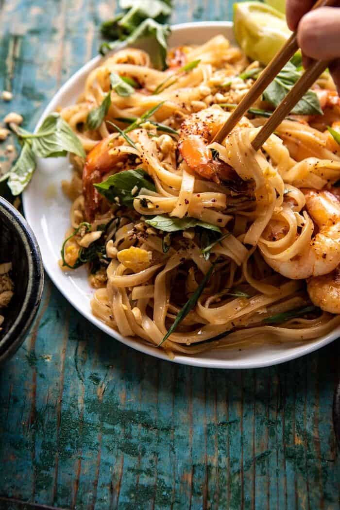 Better Than Takeout Garlic Butter Shrimp Pad Thai | halfbakedharvest.com #padthai #garlicbutter side angled photo of Better Than Takeout Garlic Butter Shrimp Pad Thai with chopsticks picking up the noodles