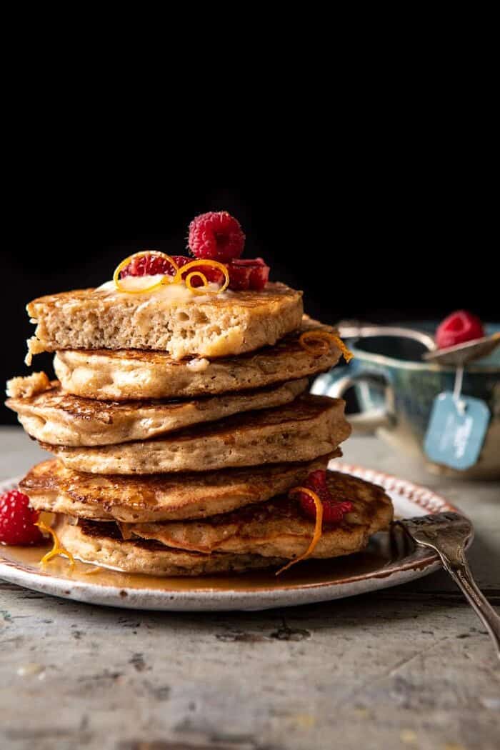 Earl Grey Lemon Ricotta Pancakes with Salted Maple Butter | halfbakedharvest.com side angled photo of Earl Grey Lemon Ricotta Pancakes with Salted Maple Butter with a bite taken out of top pancake