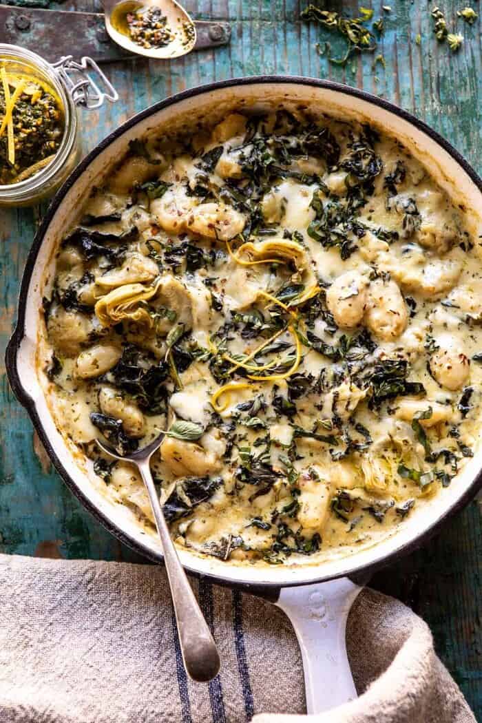 Skillet Baked Creamy Pesto Spinach and Artichoke Gnocchi | halfbakedharvest.com #gnocchi #easyrecipes #oneskillet overhead photo of Skillet Baked Creamy Pesto Spinach and Artichoke Gnocchi