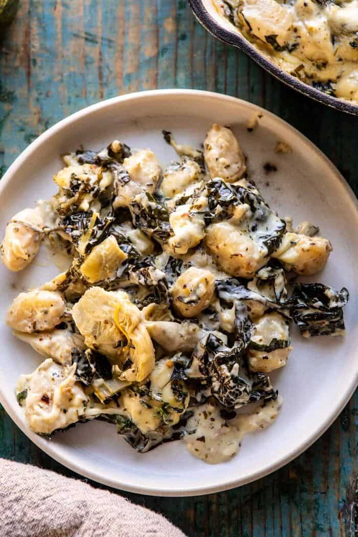 Skillet Baked Creamy Pesto Spinach and Artichoke Gnocchi | halfbakedharvest.com #gnocchi #easyrecipes #oneskillet overhead photo of Skillet Baked Creamy Pesto Spinach and Artichoke Gnocchi on serving plate