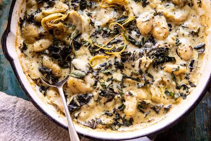 Skillet Baked Creamy Pesto Spinach and Artichoke Gnocchi | halfbakedharvest.com #gnocchi #easyrecipes #oneskillet horizontal photo of Skillet Baked Creamy Pesto Spinach and Artichoke Gnocchi