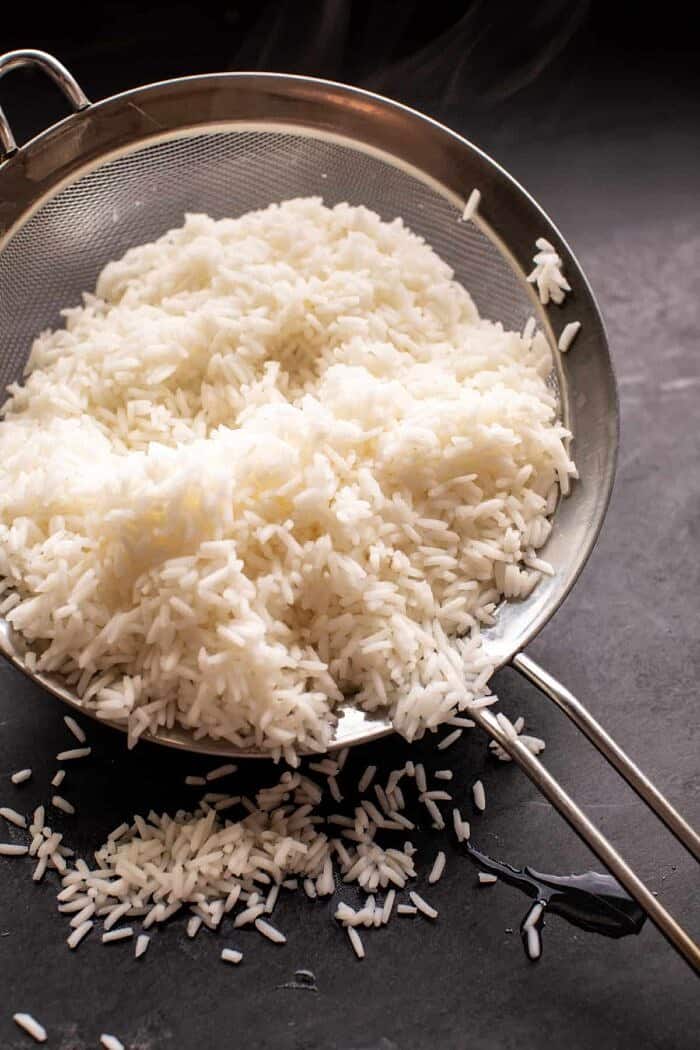 Crispy Persian Rice (Tahdig) with Spiced Golden Chickpeas | halfbakedharvest.com par cooked rice in mesh sieve after boiling