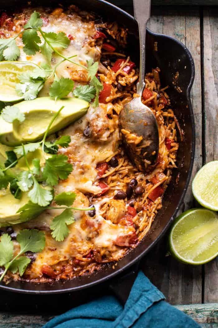 One Skillet Cheesy Cuban Chicken Rice Bake | halfbakedharvest.com overhead close up photo of One Skillet Cheesy Cuban Chicken Rice Bake with spoon in skillet and portion of rice removed