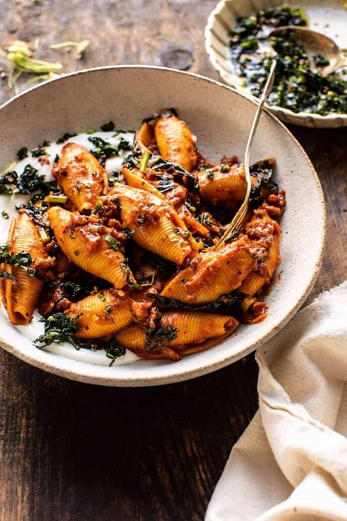 side angled photo of Unstuffed Spicy Tomato Basil Shells with Whipped Ricotta with fork in bowl 
