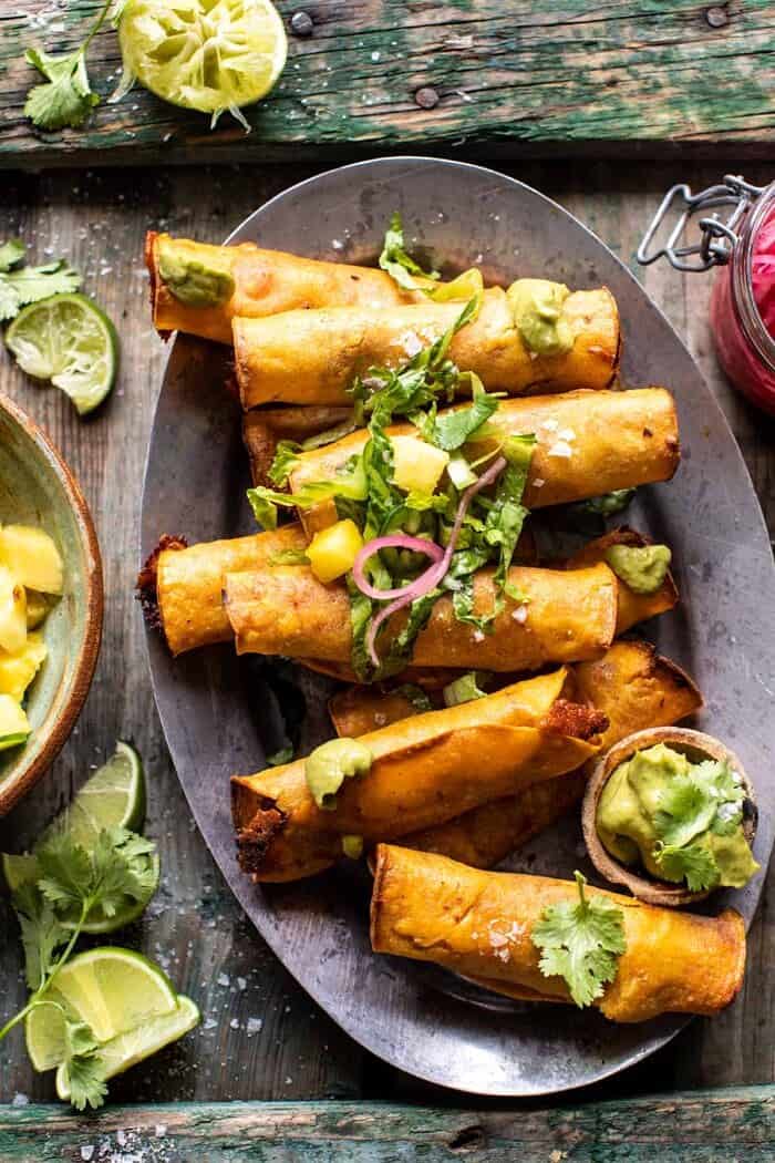 Crispy Chicken Tinga Taquitos with Salty Lime Avocado Crema | halfbakedharvest.com overhead close up photo of Crispy Chicken Tinga Taquitos with Salty Lime Avocado Crema