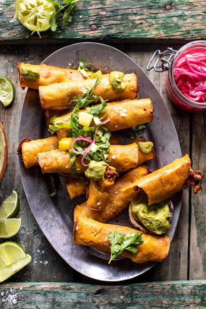 Crispy Chicken Tinga Taquitos with Salty Lime Avocado Crema | halfbakedharvest.com overhead photo of Crispy Chicken Tinga Taquitos with Salty Lime Avocado Crema