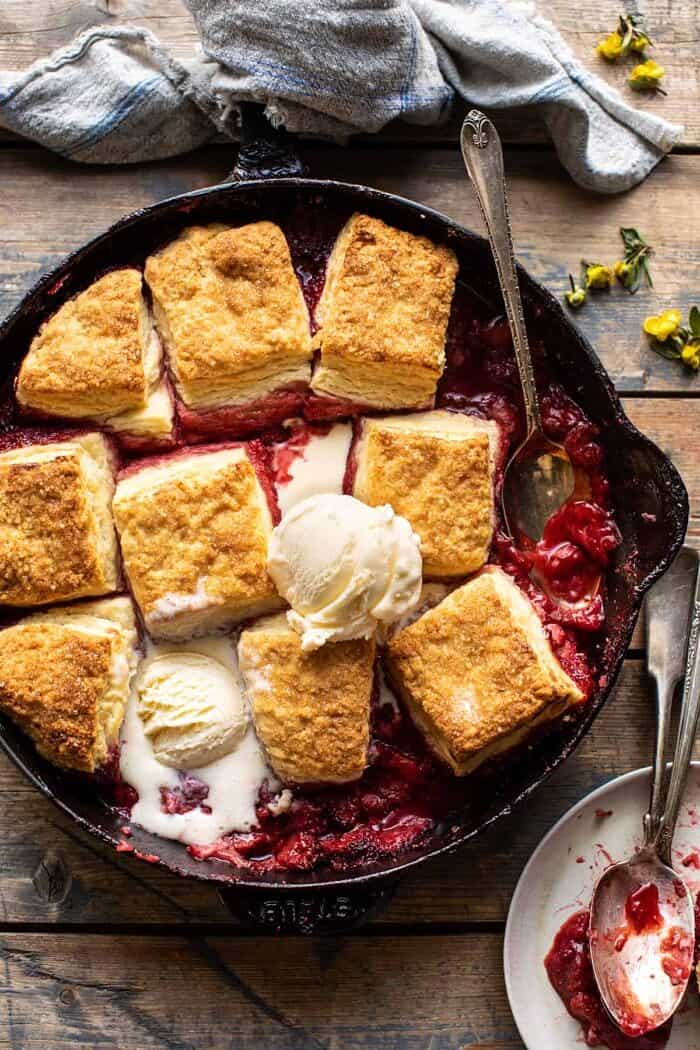 Skillet Strawberry Bourbon Cobbler with Layered Cream Cheese Biscuits | halfbakedharvest.com overhead photo of Skillet Strawberry Bourbon Cobbler with Layered Cream Cheese Biscuits with ice cream in skillet