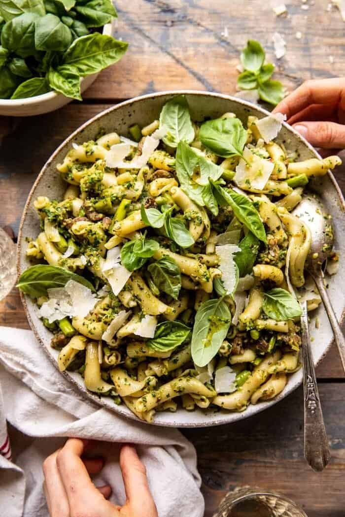 overhead photo of One Pot Lemon Basil, Asparagus, and Sausage Pasta with hands on bowl 