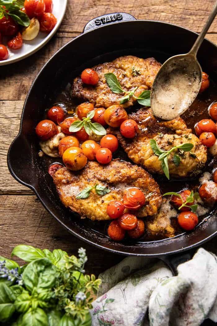 20 Minute Florentine Butter Chicken with Burst Cherry Tomatoes | halfbakedharvest.com overhead photo of 20 Minute Florentine Butter Chicken with Burst Cherry Tomatoes in skillet with spoon pouring butter over chicken