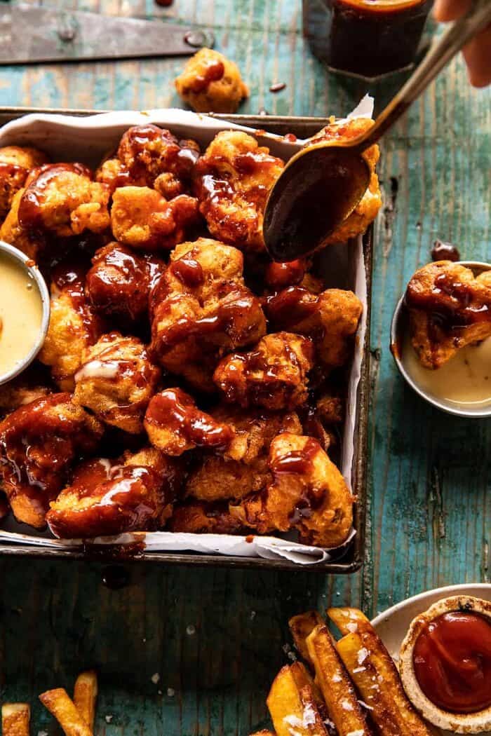 Crispy Beer Battered BBQ Cauliflower Nuggets | halfbakedharvest.com overhead photo of Crispy Beer Battered BBQ Cauliflower Nuggets being drizzled with BBQ sauce