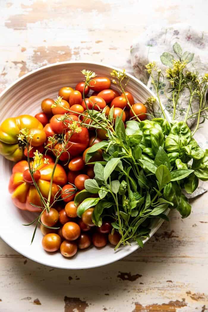 overhead photo of raw tomatoes and herbs in bowl 