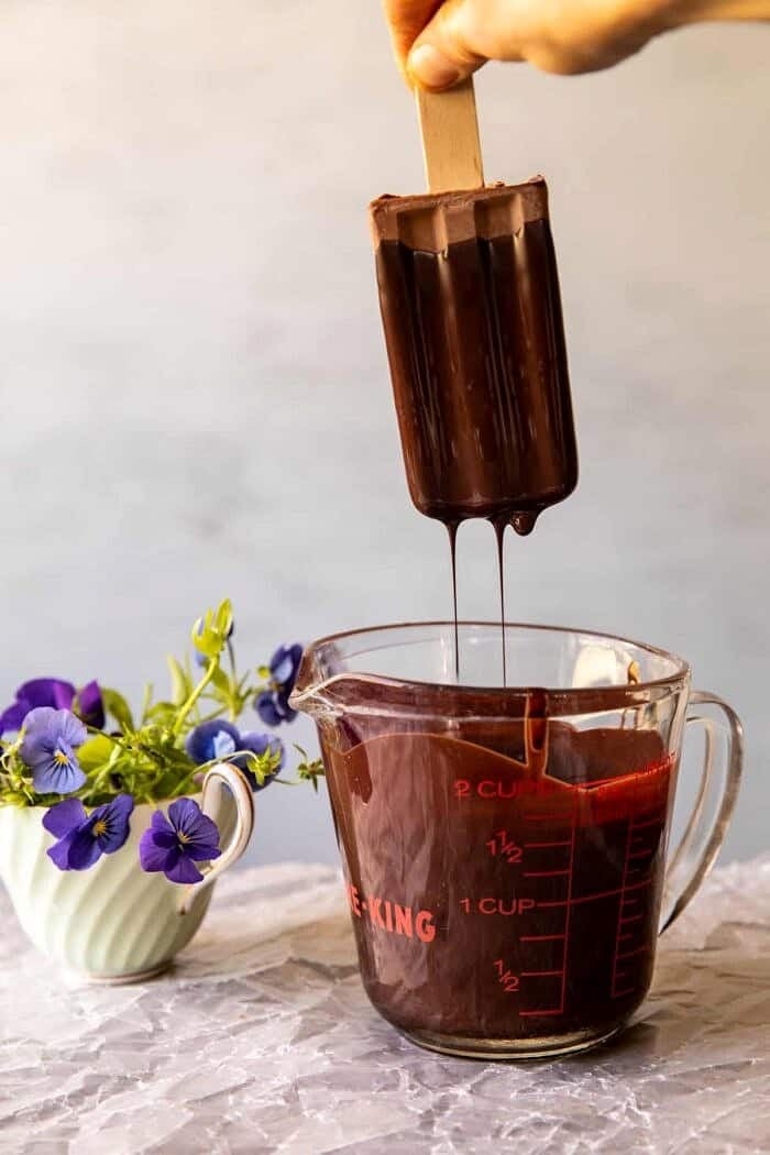 action photo of dipping Creamy Vegan Chocolate Fudge Pops in chocolate magic shell