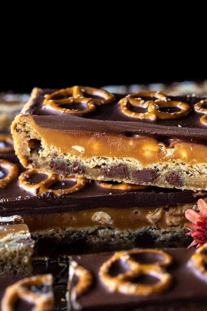 Salted Pretzel Chocolate Chip Cookie Snickers Bars | halfbakehavrest.com side angled photo of up photo of Salted Pretzel Chocolate Chip Cookie Snickers Bars