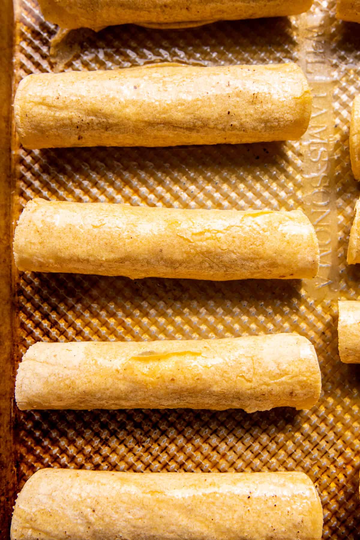 Taquitos on baking sheet before baking