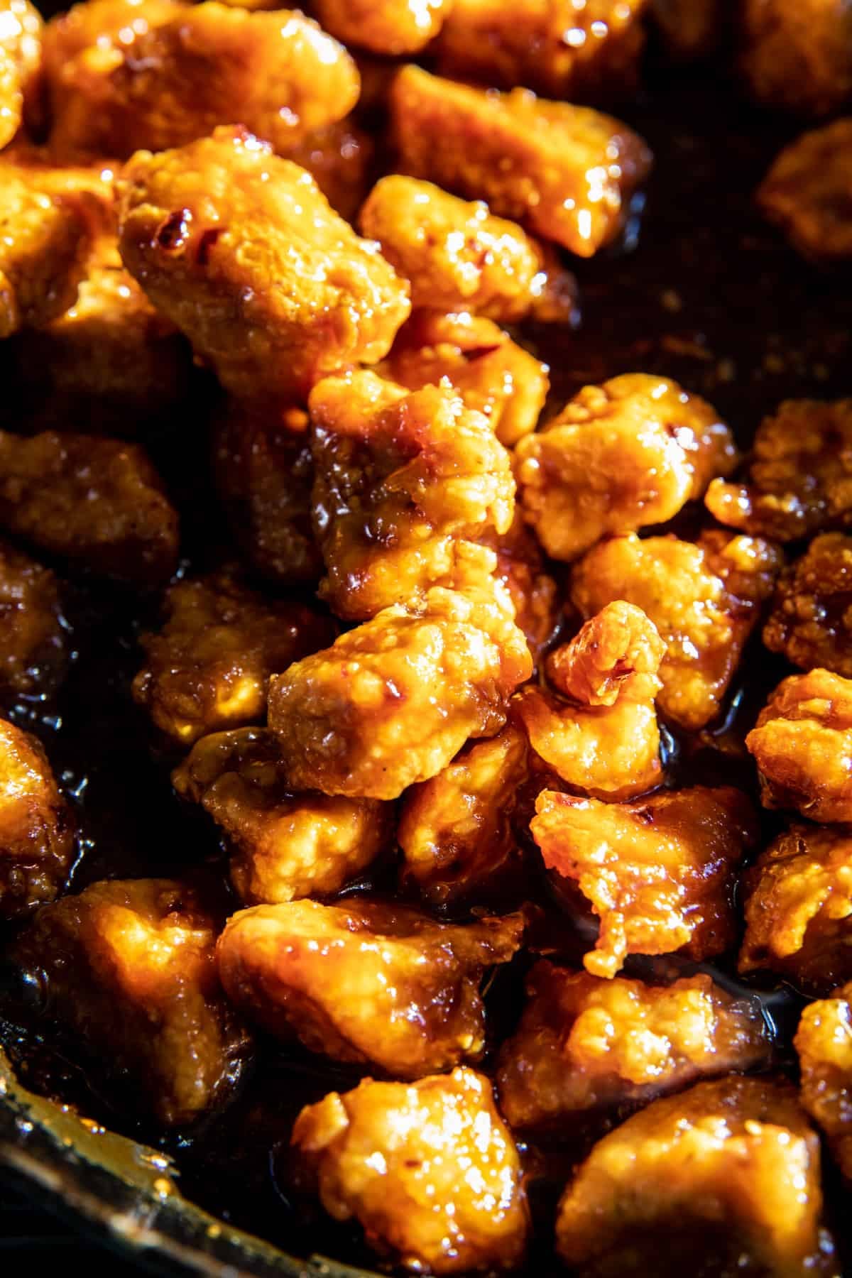 zoom in photo of orange chicken cooking in skillet